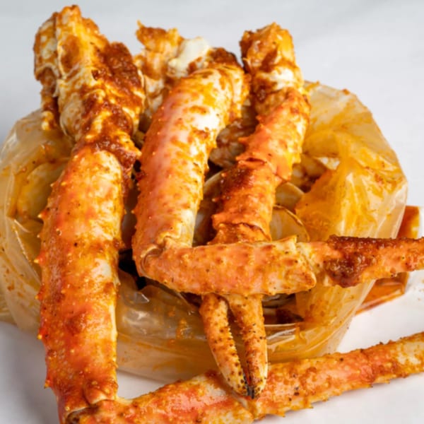 Spicy king crab legs and claws in a clear bag, ready to be served from Crab N' Spice.