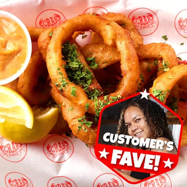 Golden fried onion rings with parsley, lemon, and dipping sauce, labeled "Customer's Fave!" at Crab N' Spice.