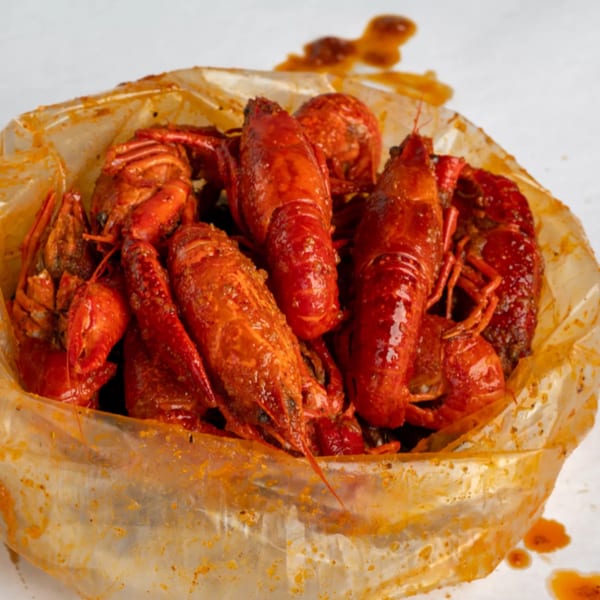 Spicy red crawfish, seasoned with spices, served in a clear plastic bag from Crab N' Spice.