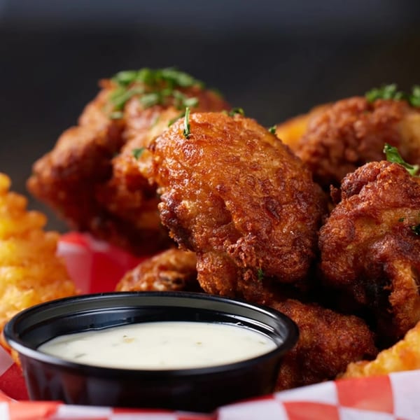 Crispy fried seafood, possibly shrimp or crab, with waffle fries and a side of dipping sauce.