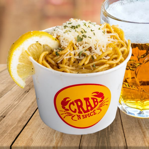 Crab N' Spice noodles with parmesan and parsley, a lemon wedge, and a glass of beer.